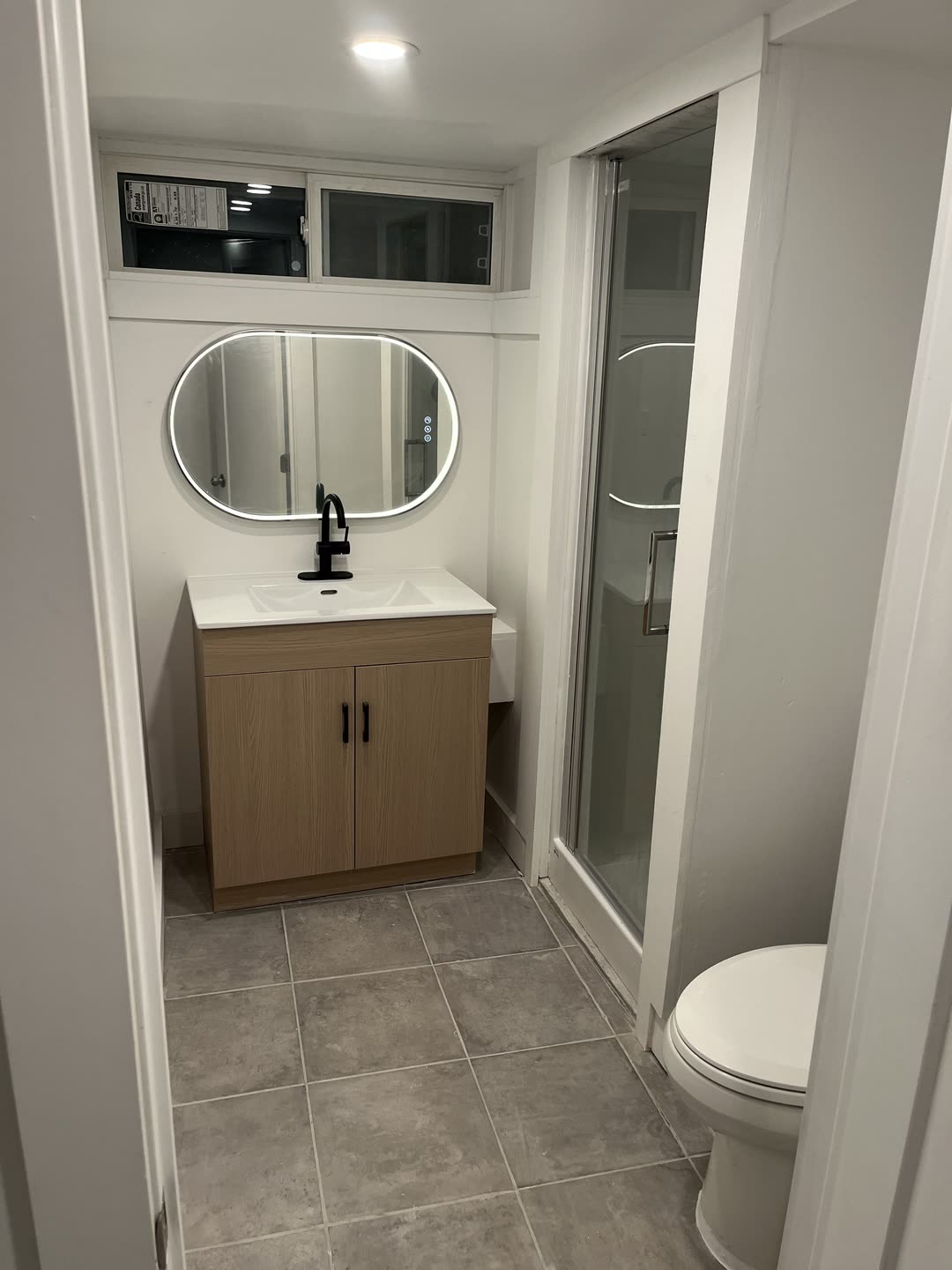 Bathroom renovation with wood vanity and LED mirror