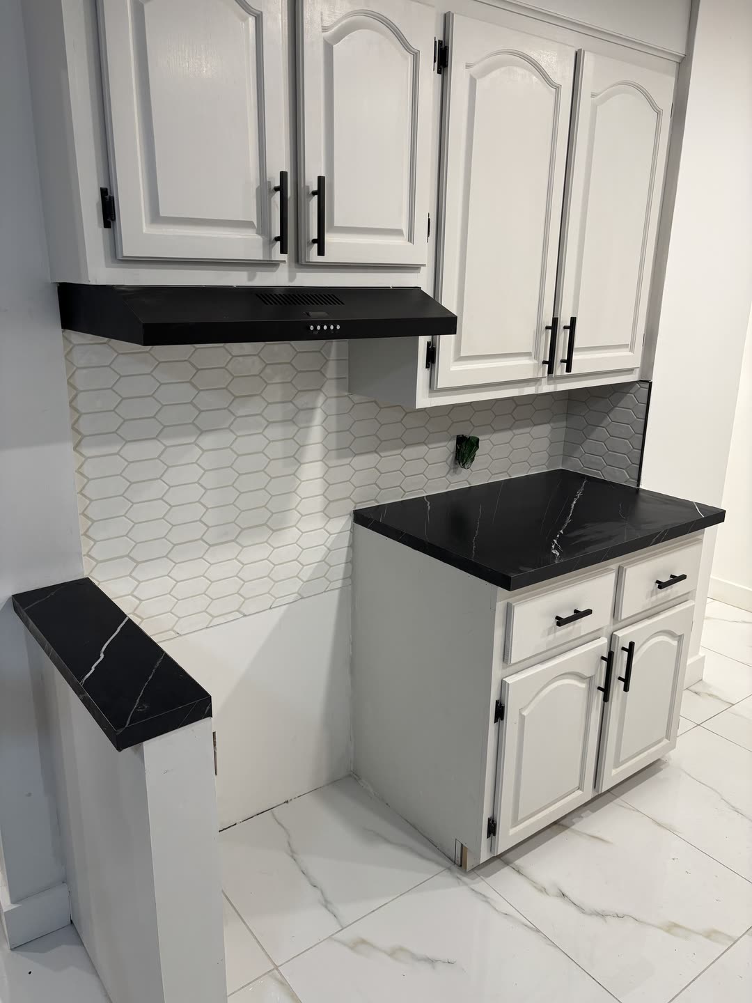 Kitchen detail showing hex tile backsplash and range hood